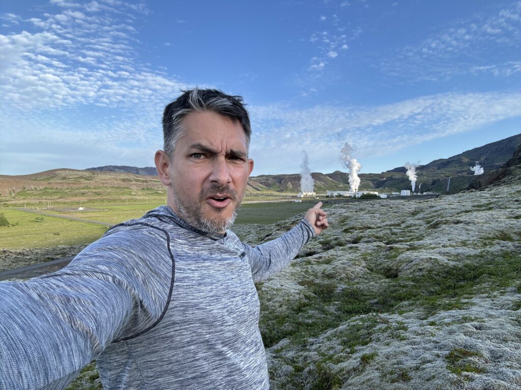 matt doing a selfie pointing at the geothermal plant