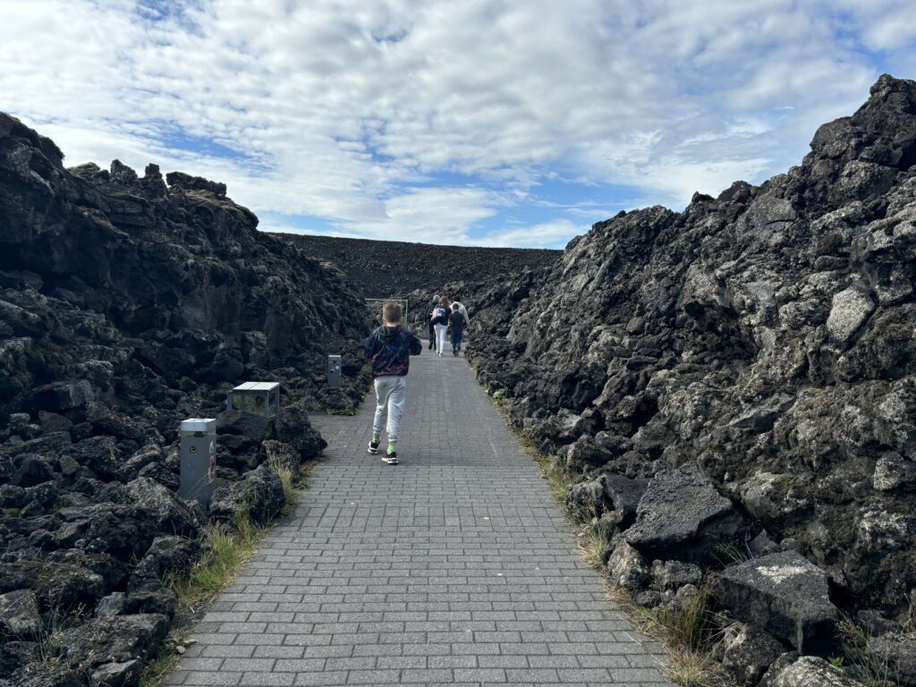 Max walking out of the blue lagoon pathway with volcanic rock all around him.